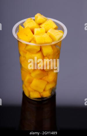 Cubi Mango maturi o pezzi tagliati disposti in vetro trasparente con sfondo nero. Foto Stock