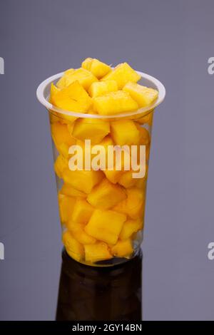 Cubi Mango maturi o pezzi tagliati disposti in vetro trasparente con sfondo nero. Foto Stock