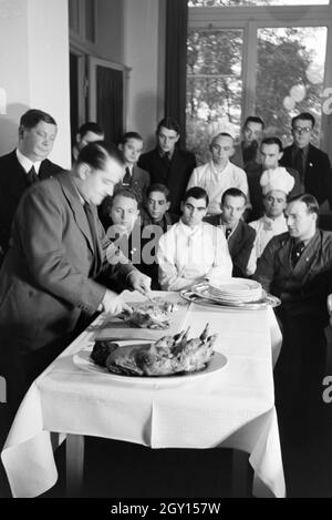 Bei einer Veranstaltung der Reichskochschule erklärt ein Meisterkoch den Lehrlingen das Richtige Filetieren, Deutschland 1930er Jahre. Un master chef è presentare il modo corretto di sfilettatura ai partecipanti nel corso di un seminario della Reichskochschule, Germania 1930s. Foto Stock