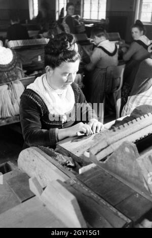 Eine Zigarrenrollerin in Marburger Tracht bei der Arbeit in einer Zigarrenfabrik bei Marburg, Deutschland 1930er Jahre. Una femmina di sigaro a rulli che indossa un abito di Marburg / costume di lavorare in un tessuto di sigaro vicino a Marburg, Germania 1930s. Foto Stock