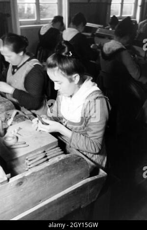 Eine Zigarrenrollerin in Marburger Tracht bei der Arbeit in einer Zigarrenfabrik bei Marburg, Deutschland 1930er Jahre. Una femmina di sigaro a rulli che indossa un abito di Marburg / costume di lavorare in un tessuto di sigaro vicino a Marburg, Germania 1930s. Foto Stock