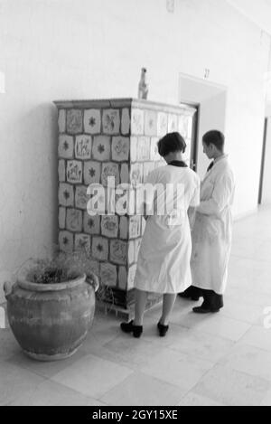 Zwei Schüler der Fachschule für Keramik in Höhr-Grenzhausen betrachten die individuell gestalteten Kacheln des Kachelofens im Flur der Schule, Deutschland 1930er Jahre. Due studenti del Collegio per la Ceramica di Höhr-Grenzhausen guardando il progettato individualmente le piastrelle della stufa in maiolica nel corridoio della scuola, Germania 1930s. Foto Stock