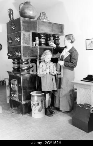 Eine Töpfermeisterin aus dem Kannenbäckerland zeigt einem kleinen Mädchen einen fertig gebrannten Tonkrug, Deutschland 1930er Jahre. Un Maestro vasaio sta mostrando un gres finito caraffa per una bambina, Germania 1930s. Foto Stock