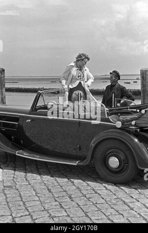 Eine Frau unterhält sich mit einem Parkwächter einer Garage in Norddeich, Deutschland 1930er Jahre. Una donna a parlare con un operatore di parcheggio di un garage di Norddeich, Germania 1930s. Foto Stock