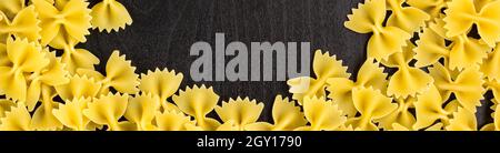 Banner di cornice di un mucchio di pasta di farfalle su sfondo nero scuro con copyspace Foto Stock
