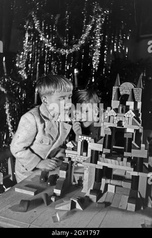 Zwei Jungen spielen am Weihnachtsabend mit den neuen Bauklötzen, Deutschland 1938. Due ragazzi giocare con il nuovo set di blocchi giocattolo sotto l albero di natale, Germania 1930 Foto Stock