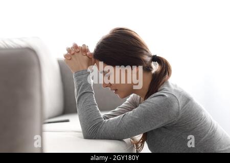 Triste disperata giovane europea infelice che soffre di disturbi mentali pregando per aiuto e recupero Foto Stock