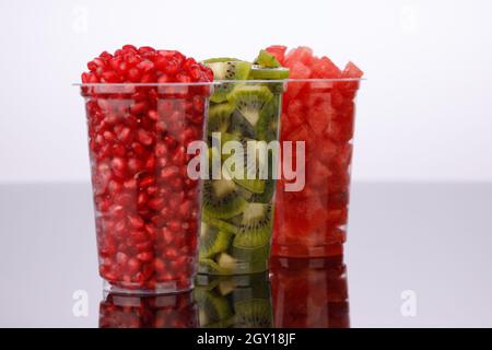 Watermelon , melograno e fette di Kiwi disposte in due bicchieri trasparenti con fondo bianco, isolati Foto Stock