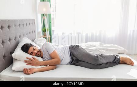 Corpo intero di uomo arabo calmo che dorme bene sul lato, riposante, banner, spazio libero Foto Stock