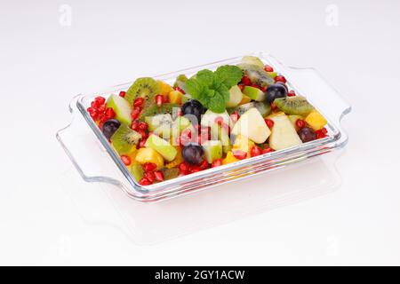 Insalata di frutta mista disposta in un vasellame rettangolare trasparente e guarnita con foglie di menta. Foto Stock