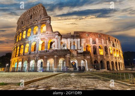 Illuminato Colosseo romano sotto le nuvole all'alba, Italia. Foto Stock