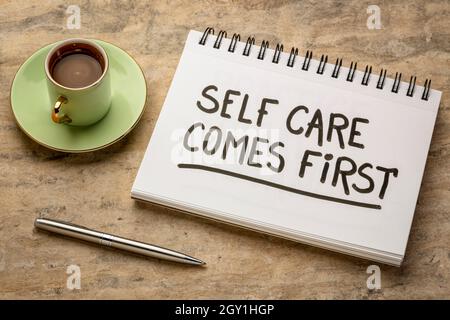 la cura di sé viene primo richiamo ispiratore - scrittura a mano in un libro di schizzo con una tazza di caffè, slogan sano di stile di vita Foto Stock