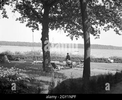 Menschen erholen sich an der Uferpromenade eines vede, Deutschland 1930er Jahre. Persone rilassarsi all'ombra a un lago, Germania 1930s. Foto Stock