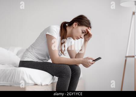 Infelice ragazza caucasica disperata leggere messaggio con cattive notizie, soffrendo di depressione e stress Foto Stock