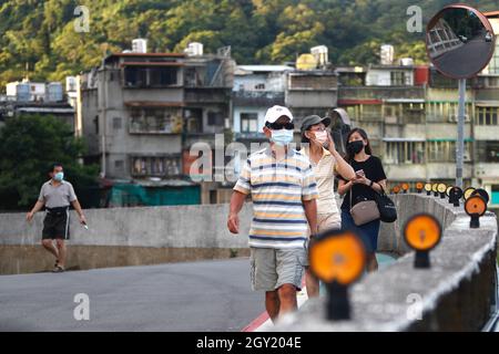 Taipei, Taiwan. 6 ottobre 2021. Le persone con maschere facciali vanno per una passeggiata in una zona residenziale di Taipei, dopo il 7° giorno consecutivo con zero casi locali Covid segnalati. Secondo il CDC di Taiwan, con il governo che mette a disposizione del pubblico un maggior numero di vaccini, tra cui AstraZeneca e BionTech, sono state abolite misure di contenimento più numerose. (Credit Image: © Daniel Ceng Shou-Yi/ZUMA Press Wire) Foto Stock