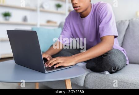 Apprendimento a distanza. Adolescente afroamericano irriconoscibile che studia online, usando il portatile a casa, primo piano Foto Stock