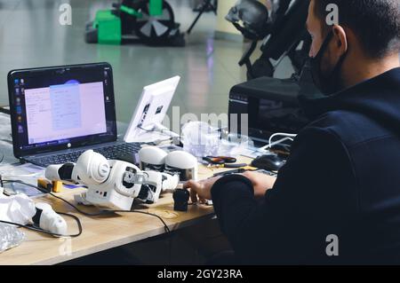 uomo che ripara un robot. Primo piano di un uomo che fissa un piccolo robot rotto Foto Stock