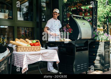 Odessa, Ucraina - Maggio, 11 2014: Cucina in cucina italiana all'aperto pizzeria ristorante con stufa a fuoco aperto e pane fresco e verdure in cestini. Foto Stock