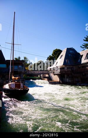 Il fiume bianco froloso attraversa una città con una barca da pesca bianca ormeggiata al molo Foto Stock
