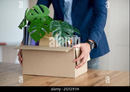 Giovane uomo con scatola di effetti personali che cessi il lavoro, cambia ufficio, riceve la promozione, avendo il primo giorno di nuovo lavoro Foto Stock
