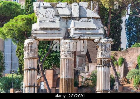 Dettagli e incisioni di antiche rovine di colonne corinzie di fronte agli alberi verdi e alle mura di mattoni rossi al Foro Romano di Venezia Foto Stock