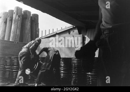 Lagerarbeiter der Rhenania Ossag Mineralölwerke AG DI AMBURGO das verladen Bitumenprodukt Mexphalt auf Schiffe, Deutschland 1930er Jahre. Warehousemen della Rhenania Ossag Mineraloelwerke AG ad Amburgo il carico di una nave con il bitume prodotto Mexphalt, Germania 1930s. Foto Stock