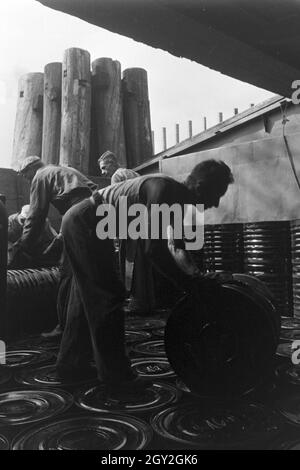 Lagerarbeiter der Rhenania Ossag Mineralölwerke AG DI AMBURGO das verladen Bitumenprodukt Mexphalt auf Schiffe, Deutschland 1930er Jahre. Warehousemen della Rhenania Ossag Mineraloelwerke AG ad Amburgo il carico di una nave con il bitume prodotto Mexphalt, Germania 1930s. Foto Stock