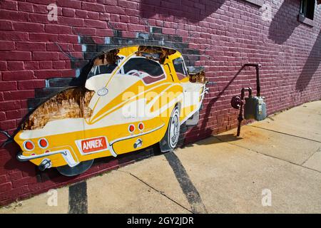 Taglio di cartone di un'auto d'epoca gialla su un muro di mattoni urbani Foto Stock