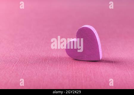 Cuore rosa valentino su sfondo rosa testurizzato con spazio copia. Macro. Mockup elemento di design per San Valentino, biglietto di auguri, banner. Foto Stock