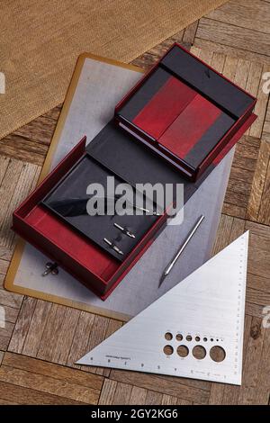 La scatola aperta rossa e nera contenente un quill si trova accanto ad un coltello e ad un bordo diritto triangolare Foto Stock