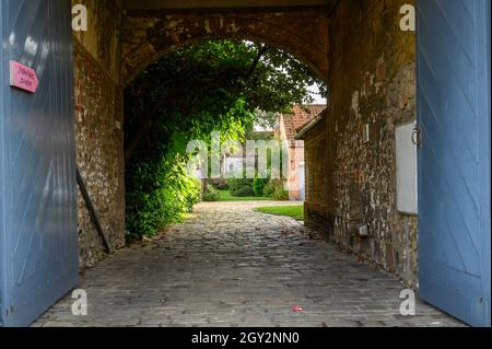 Accesso acciottolato in un cortile con vecchie case in pietra private tradizionali a Burnham Market, Norfolk, Inghilterra. Foto Stock