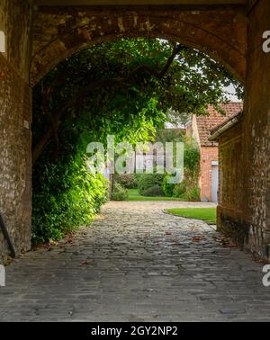 Accesso acciottolato in un cortile con vecchie case in pietra private tradizionali a Burnham Market, Norfolk, Inghilterra. Foto Stock