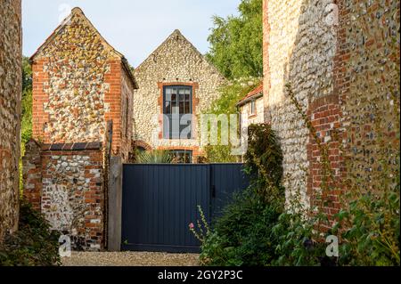 Drive e cortile recintato a vecchie case di mattoni e pietra focaia, ora casa privata, in Burnham Market, Norfolk, Inghilterra. Foto Stock