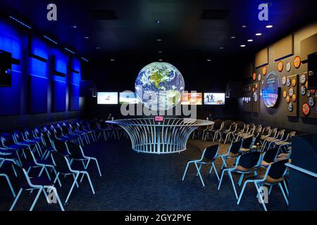 Bagliate nella sala della scienza scura con molte sedie che si affacciano su un globo sospeso Foto Stock