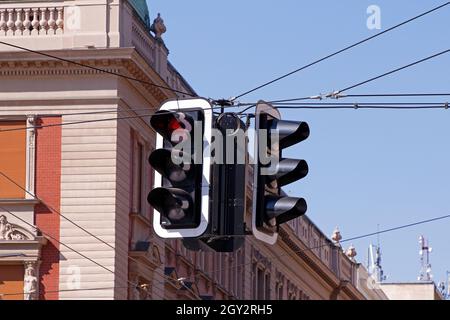 Semaforo sopra l'incrocio in città con cielo blu sullo sfondo Foto Stock