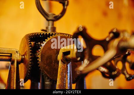 Primo piano di un'antica macchina con illuminazione arancione con ingranaggi e maniglie Foto Stock