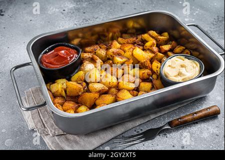 Patatas bravas tradizionale spagnolo patate snack tapas in un vassoio di acciaio sfondo grigio. Vista dall'alto Foto Stock