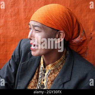 Una donna che indossa un copricapo arancione o hijab e un blazer grigio che vende peperoncini rossi in un mercato all'aperto a Bukittinggi, West Sumatra, Indonesia. Foto Stock