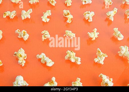 Popcorn fresco isolato su sfondo arancione, vista dall'alto. Popcorn su sfondo colorato. Concetto minimo di cibo. Contenuti di intrattenimento, film e video Foto Stock