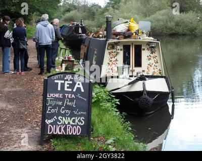 Vista di un'affollata teashop che vende da una graziosa chiatta del canale sul Canal Grande Union vicino a Watford Hertfordshire Regno Unito Foto Stock