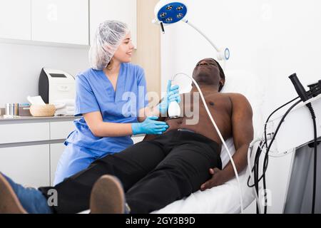 uomo americano che ha cavitazione procedura in clinica di bellezza Foto Stock