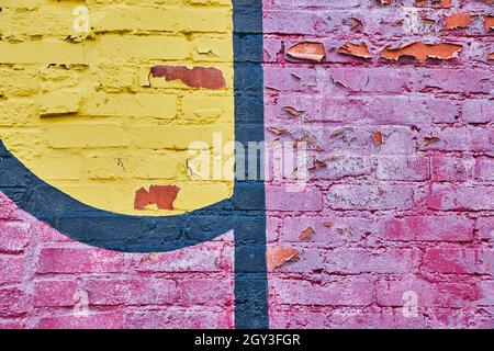 Primo piano di graffiti rossi, neri e gialli su mattoni Foto Stock
