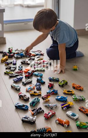 Ridendo bambino ragazzo carino che giace in cerchio di auto modello giocattoli hot ruote collezione vista dall'alto Foto Stock