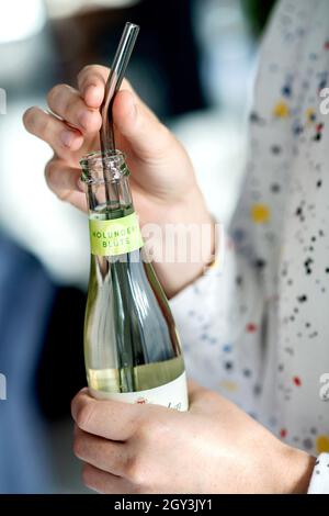 Oldenburg, Germania. 01 ottobre 2021. Una giovane donna tiene in mano una bottiglia di champagne con un bicchiere di cannuccia da bere. Credit: Hauke-Christian Dittrich/dpa/Alamy Live News Foto Stock