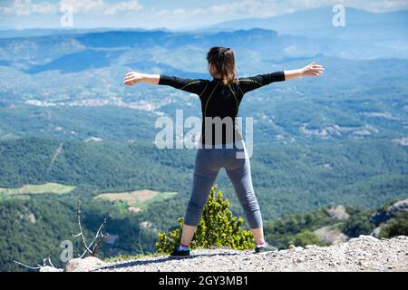 Vista posteriore della donna con mani rialzate in cima alla montagna Foto Stock