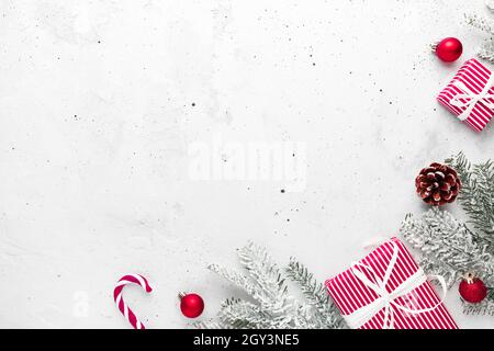 Natale, nuovo anno grigio calcestruzzo piatto con rosso bianco regalo scatole vista dall'alto. Nastro regalo e carta da imballaggio. Abete albero di Natale, coni, giocattolo Foto Stock