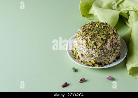 Halva con pistacchi, poche noci sparse e tovagliolo di lino verde su carta verde menta. Orientamento orizzontale. Spazio di copia. Tradizionale medio Oriente Foto Stock