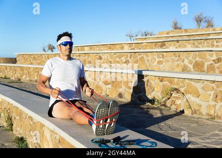 Giovane uomo caucasico che si esercita con una fascia di gomma nel parco Foto Stock