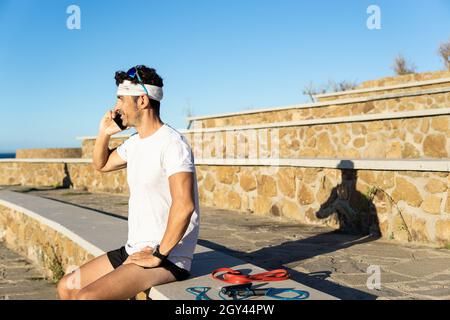 Giovane uomo caucasico che parla su uno smartphone in un parco all'aperto w Foto Stock