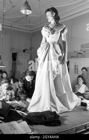 Ein Model und Schneiderinnen bei der Anprobe eines Kleides von Modeschöpferin Annemaria Geise; Deutschland ca. 1939. Un modello e sartors provando un abito di moda designer Annemaria Geise; Germania ca. 1939. Foto Stock